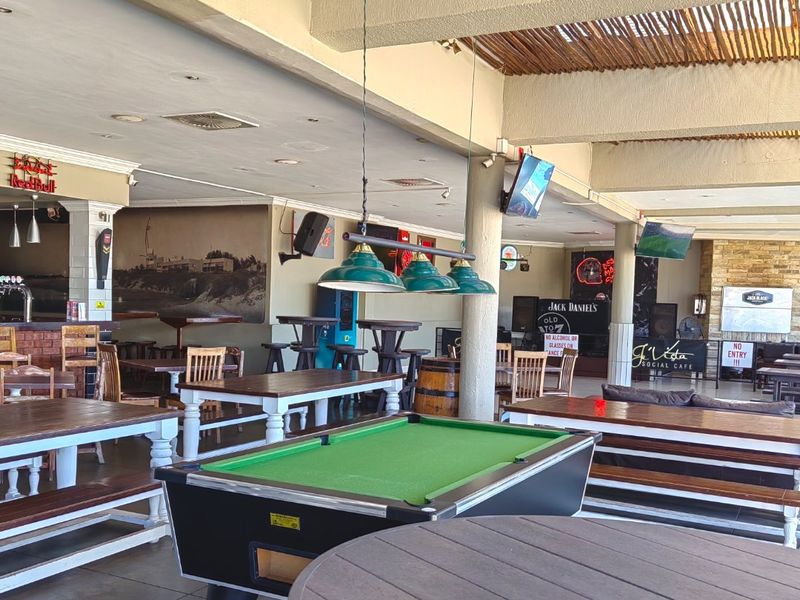 Spacious commercial bar area featuring exposed timber ceilings, structural columns, a stone feature wall, and a built-in bar counter.
