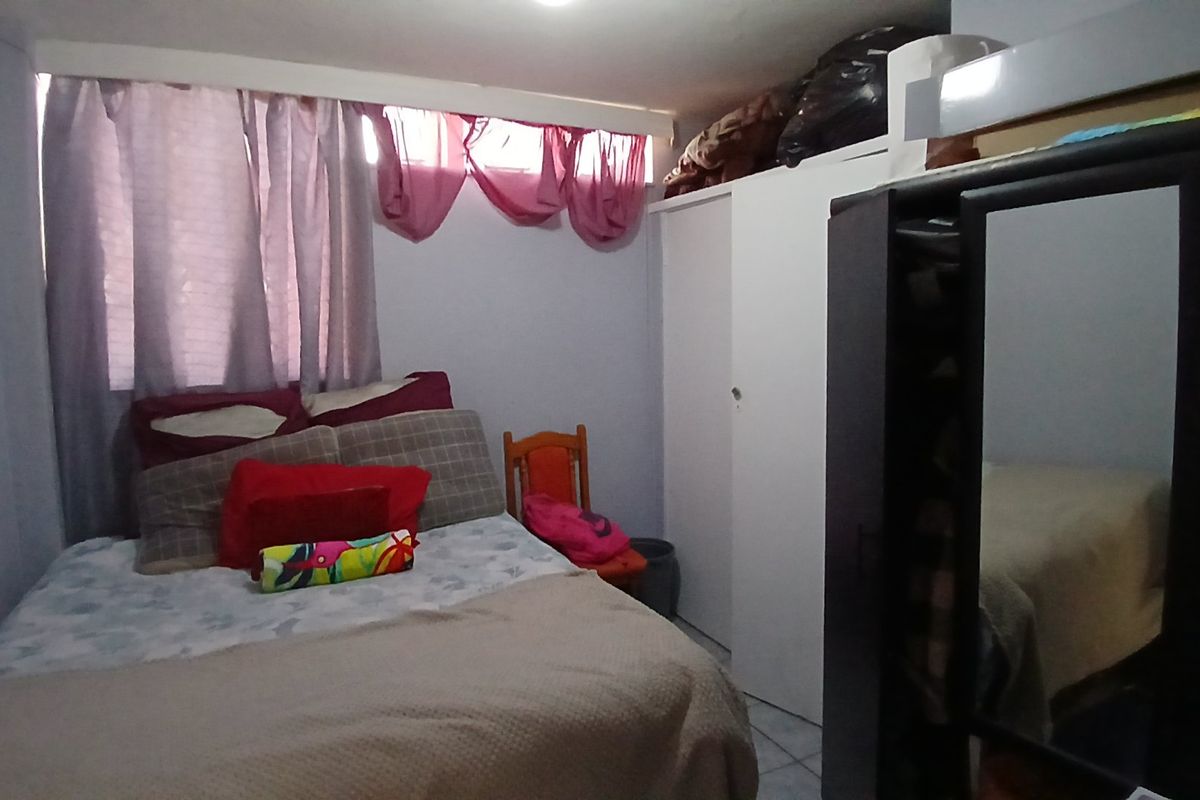 A functional bedroom featuring a built-in wardrobe and tiled flooring, providing a practical living space.