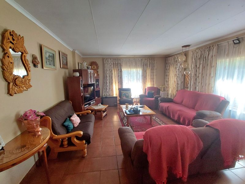 Spacious living room featuring tiled flooring and large windows with curtain tracks, offering a comfortable and functional layout for family relaxation.