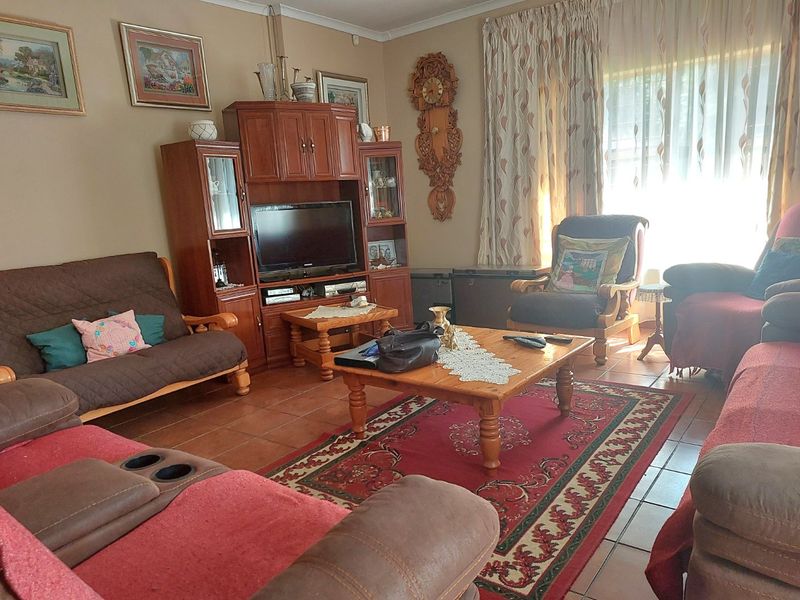 A traditional living room featuring tiled flooring and large windows with curtain treatments, offering a comfortable and functional space for relaxation.
