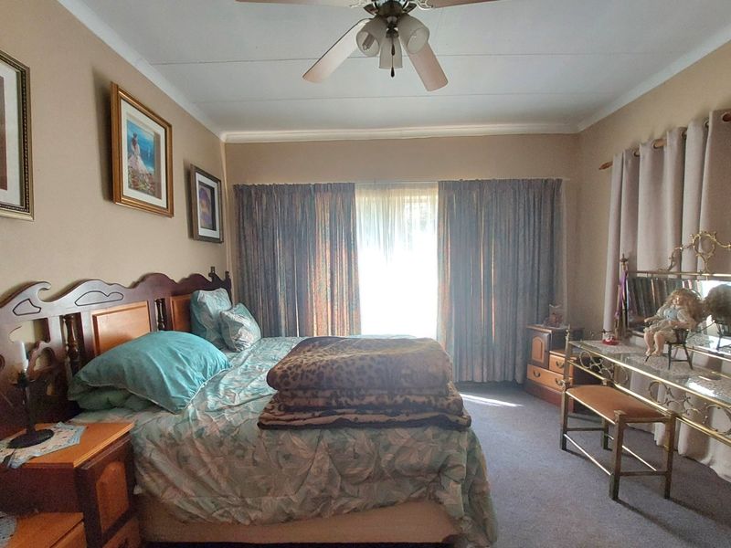 A well-lit bedroom featuring carpeted flooring and a ceiling fan, offering a comfortable and functional living space.