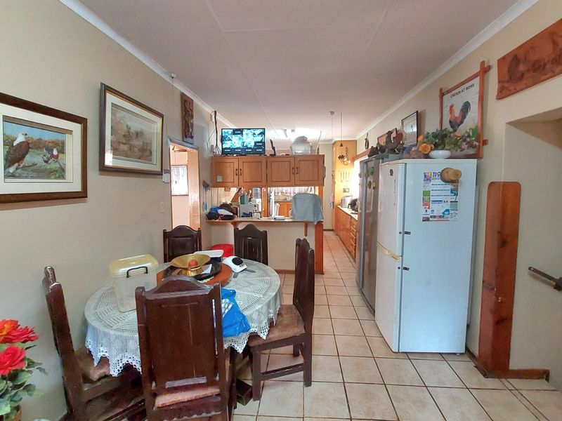 Open-plan dining and kitchen area featuring tiled flooring, wooden cabinetry, and a breakfast counter, offering a functional layout for daily living.