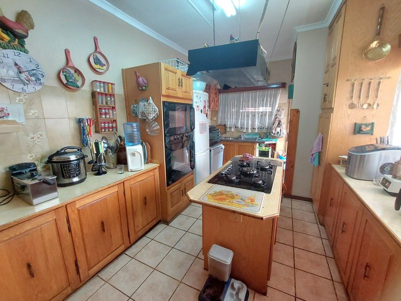 A functional kitchen featuring wooden cabinetry, a central island with a gas cooktop, built-in double oven, and tiled flooring.