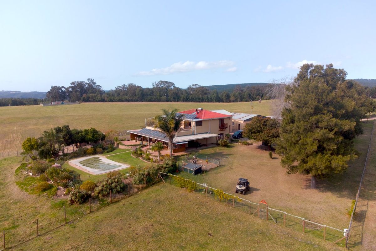 Aerial view of a farm property featuring a main residence with solar panels, a swimming pool, and expansive surrounding grounds.