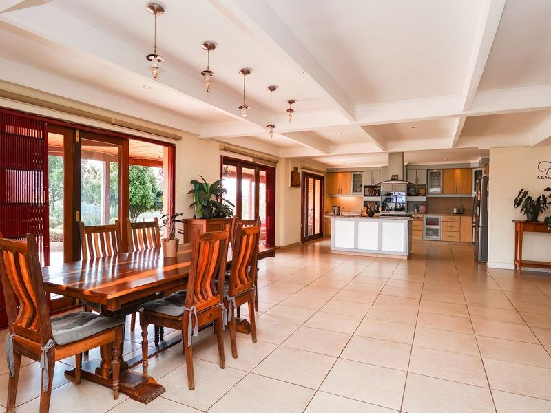 Spacious open-plan living and dining area featuring tiled floors, exposed beam ceilings, and a well-appointed kitchen with a central island and sliding door access.
