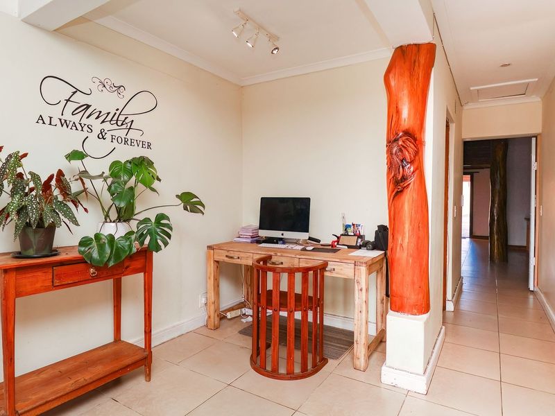 A functional hallway area featuring tiled flooring, track lighting, and a unique decorative carved wooden pillar, providing access to adjacent rooms.