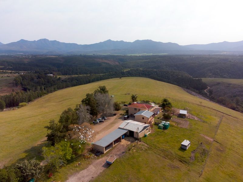 Aerial view of a farm property featuring multiple outbuildings, water storage tanks, and expansive surrounding landscape with mountain views.