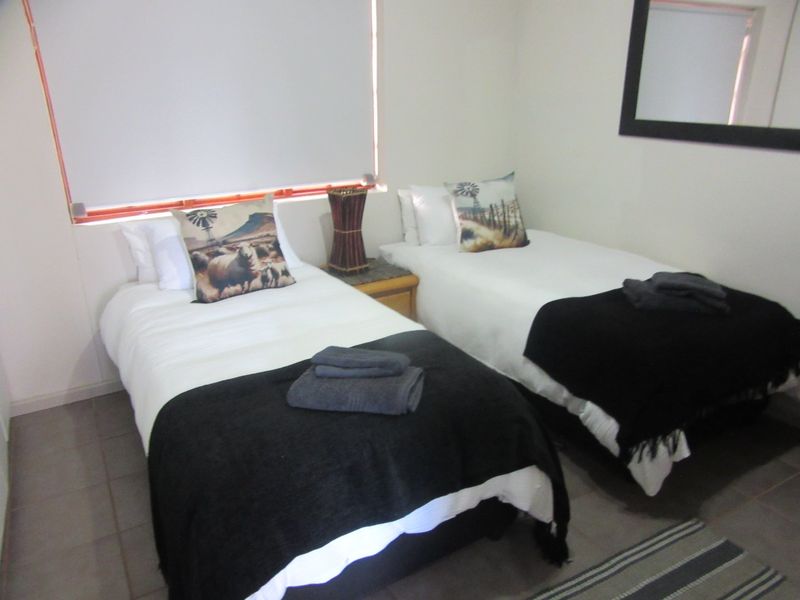 A functional bedroom featuring tiled flooring and a roller blind, providing a neutral space ready for personalization.