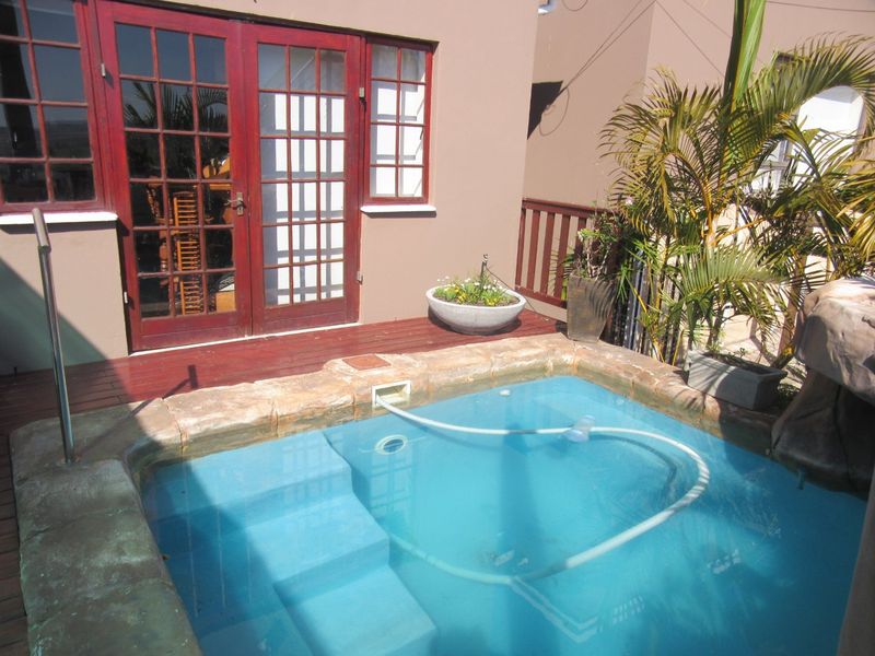 A compact plunge pool area featuring timber decking and direct access to the interior through classic timber-framed french doors.