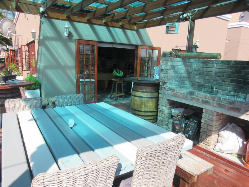 Covered outdoor patio featuring timber decking, a built-in brick braai, and a timber pergola, providing a functional space for outdoor entertaining.