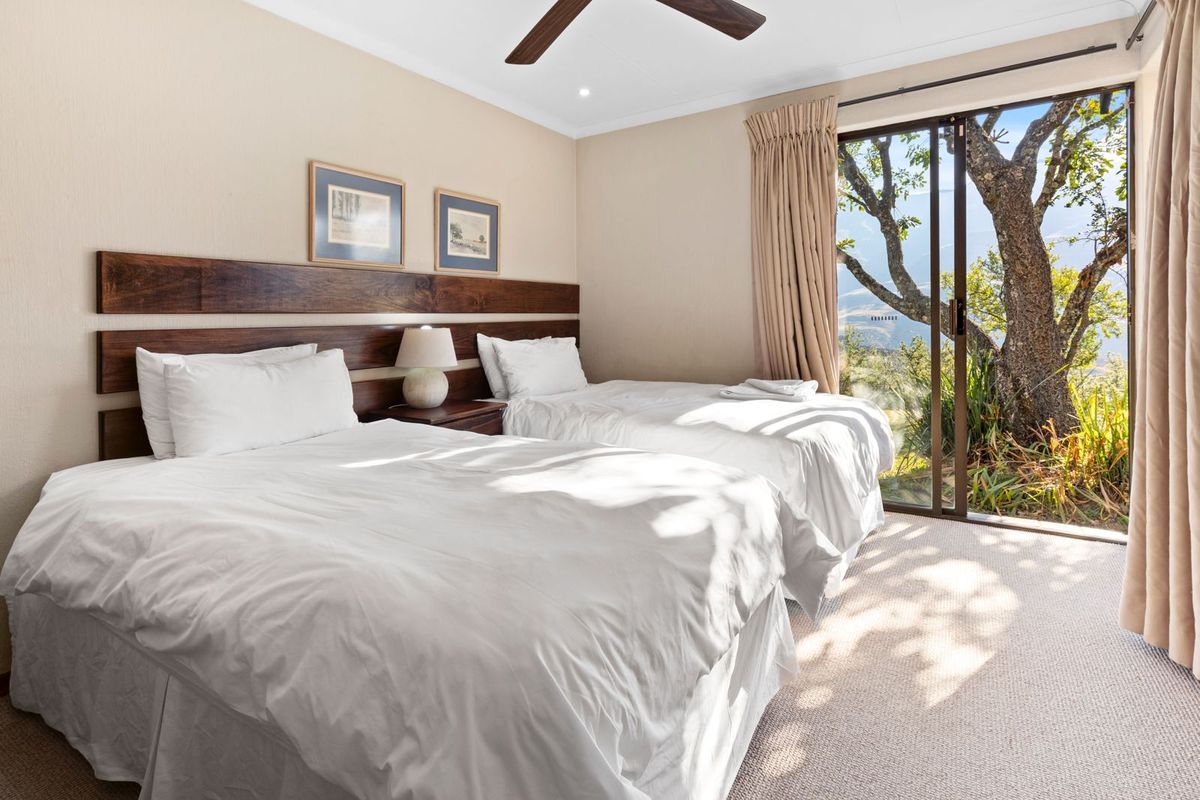 A well-maintained bedroom featuring a built-in wooden headboard, ceiling fan, and sliding glass doors providing natural light and access to the outdoor area.