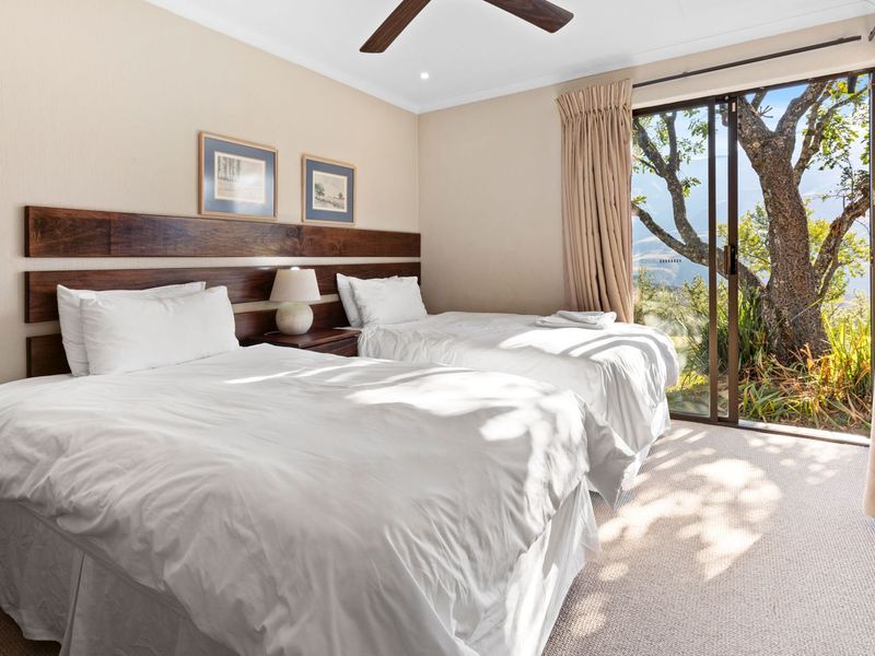 A well-maintained bedroom featuring a built-in wooden headboard, ceiling fan, and sliding glass doors providing natural light and access to the outdoor area.