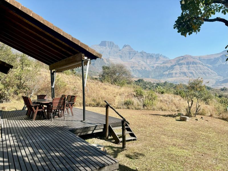 A spacious timber deck patio featuring a covered roof area, offering expansive views of the surrounding mountain landscape.