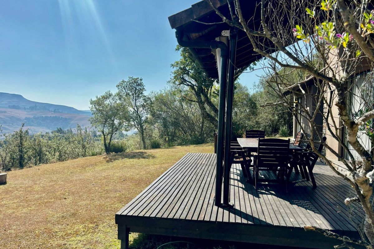 A covered timber deck patio overlooking a scenic landscape, featuring integrated guttering and direct access to the garden area.