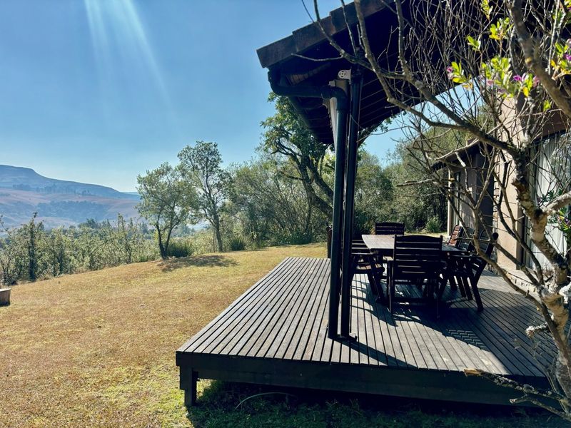A covered timber deck patio overlooking a scenic landscape, featuring integrated guttering and direct access to the garden area.