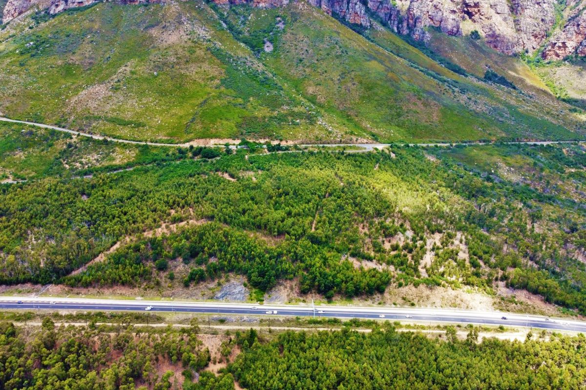 An aerial view of the farm property showcasing the expansive mountain landscape, natural forest terrain, and adjacent public road access.