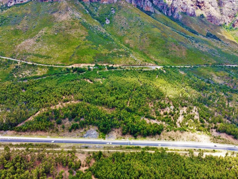 An aerial view of the farm property showcasing the expansive mountain landscape, natural forest terrain, and adjacent public road access.
