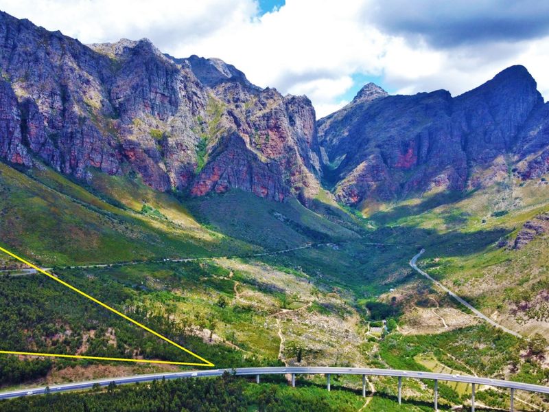 An expansive aerial view of a mountainous landscape featuring a winding road and valley, highlighting the natural beauty and topography of the farm location.