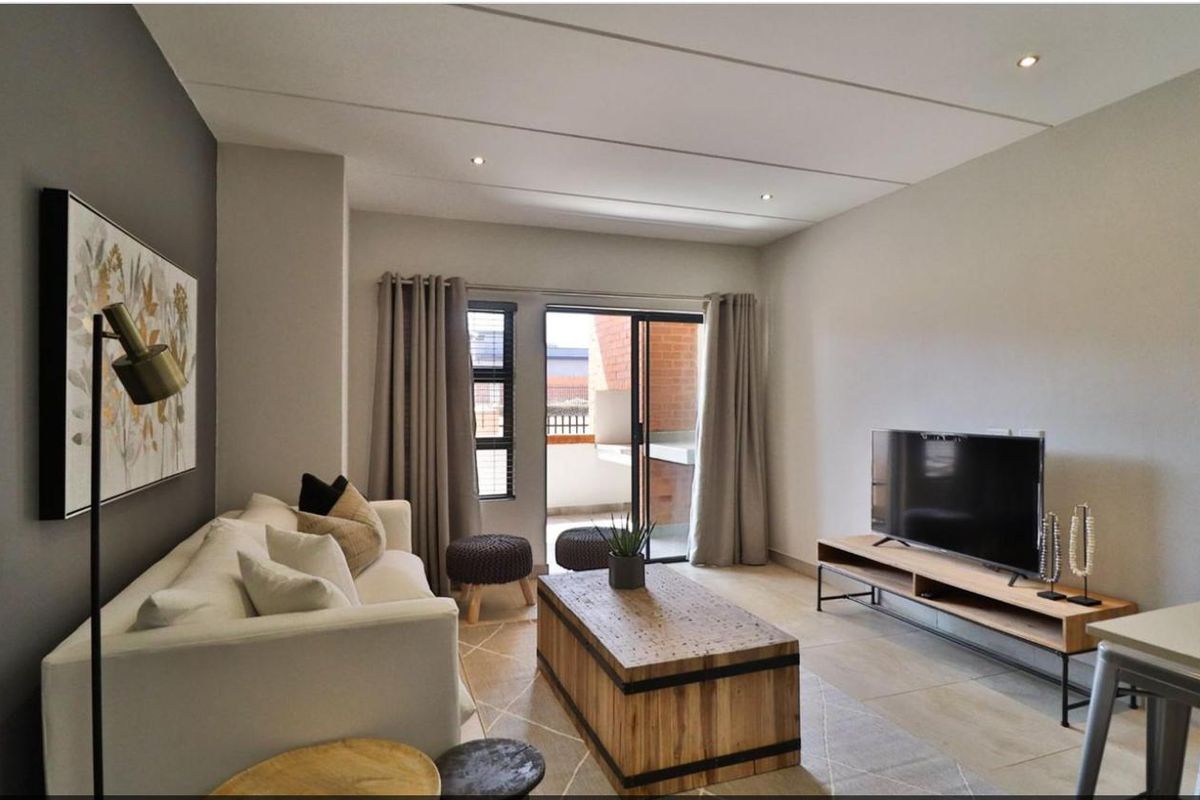 A well-maintained living room featuring tiled floors, recessed lighting, and a sliding glass door providing access to an outdoor balcony area.