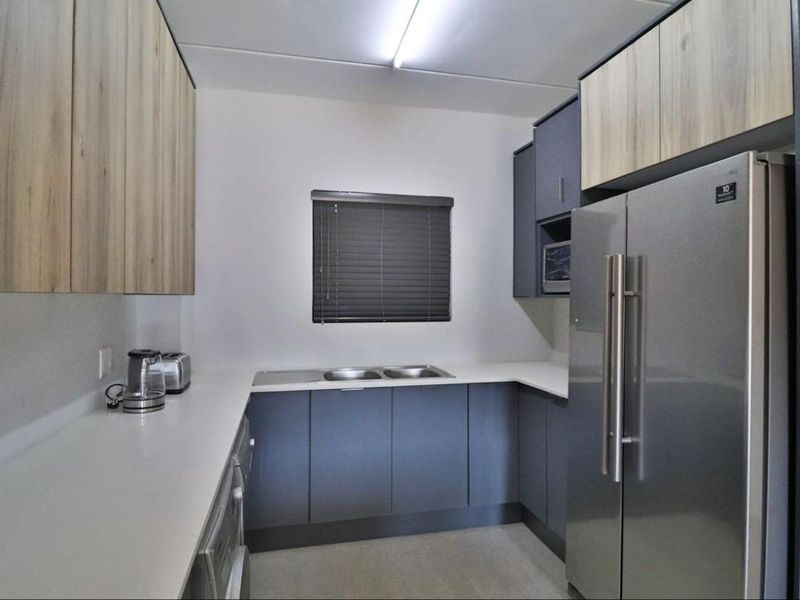 Modern kitchen featuring sleek two-tone cabinetry, ample countertop space, a double sink, and integrated microwave, offering a clean and functional culinary workspace.