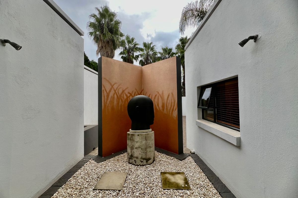 A landscaped courtyard area featuring gravel ground cover, stone pavers, and exterior wall lighting between two building sections.