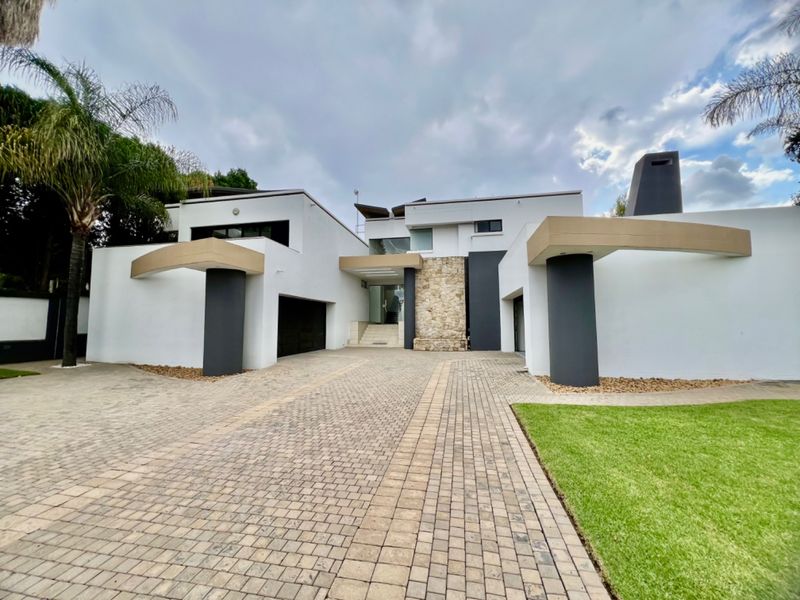 Modern architectural front facade featuring a stone-clad entrance, paved driveway, and double garage with contemporary design elements.