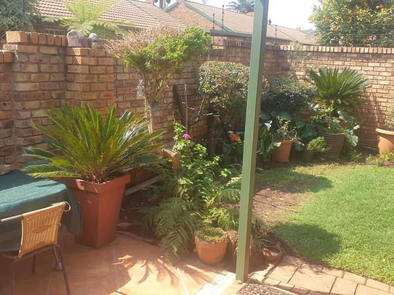 A private rear garden featuring a tiled patio area, a small lawn, and established brick boundary walls.