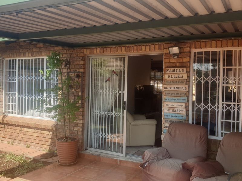 Covered patio area featuring brick walls, tiled flooring, and sliding door access with security gates, providing a functional outdoor living space.