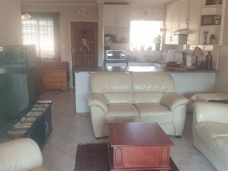 Open plan living area featuring a kitchen with built-in cabinetry and a breakfast counter, seamlessly connected to the lounge space.