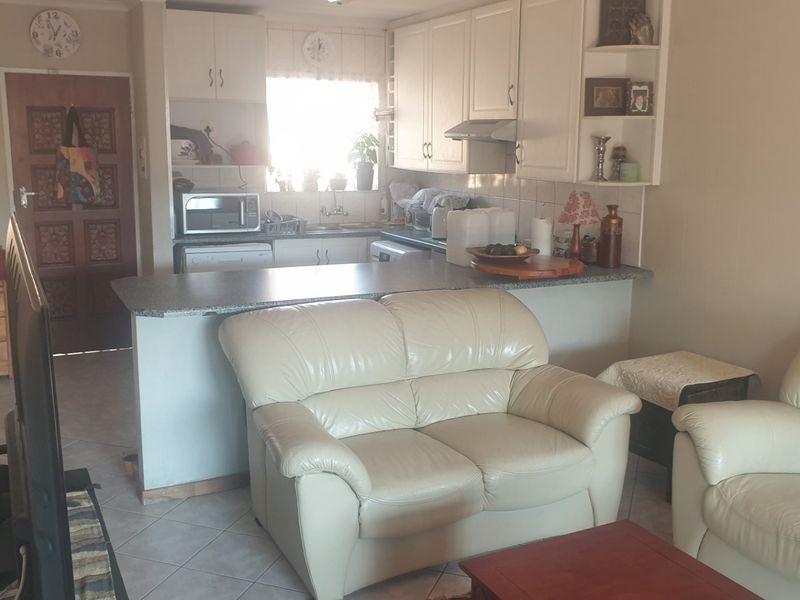Open plan living area featuring a functional kitchen with breakfast bar, ample cabinetry, and tiled flooring throughout the combined space.