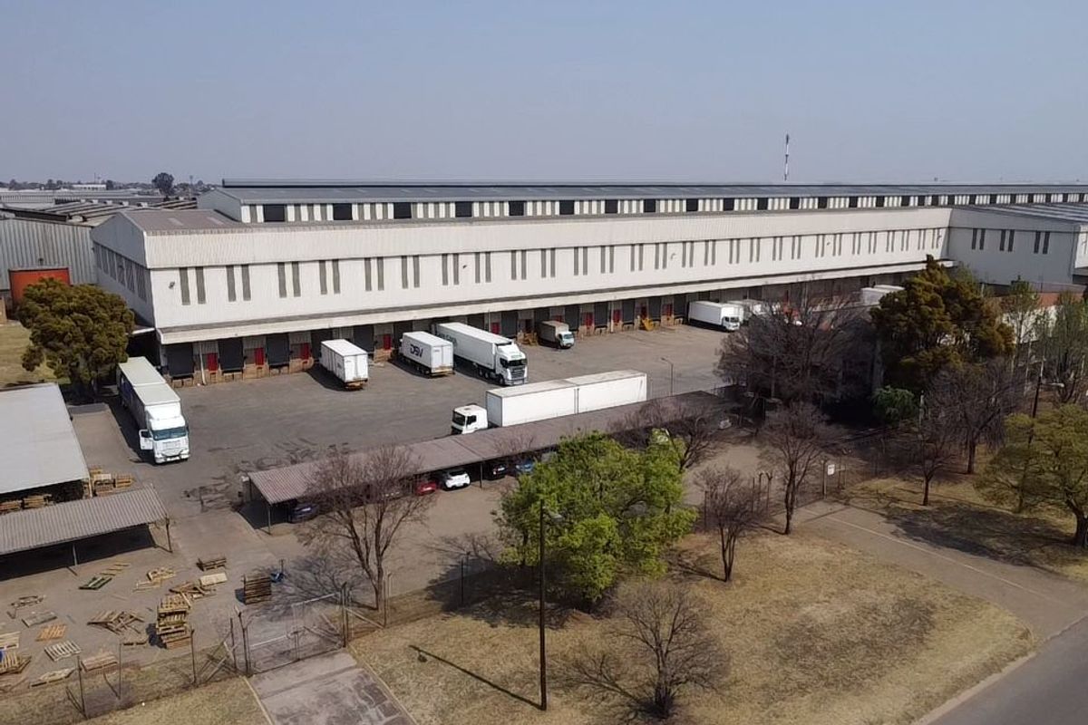 Aerial view of a large industrial warehouse facility featuring multiple loading docks, extensive yard space, and covered parking areas.
