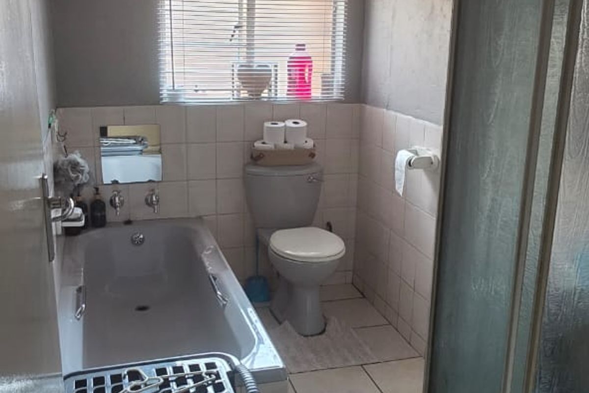 A functional bathroom featuring a bathtub, separate shower enclosure, and toilet with tiled finishes throughout.