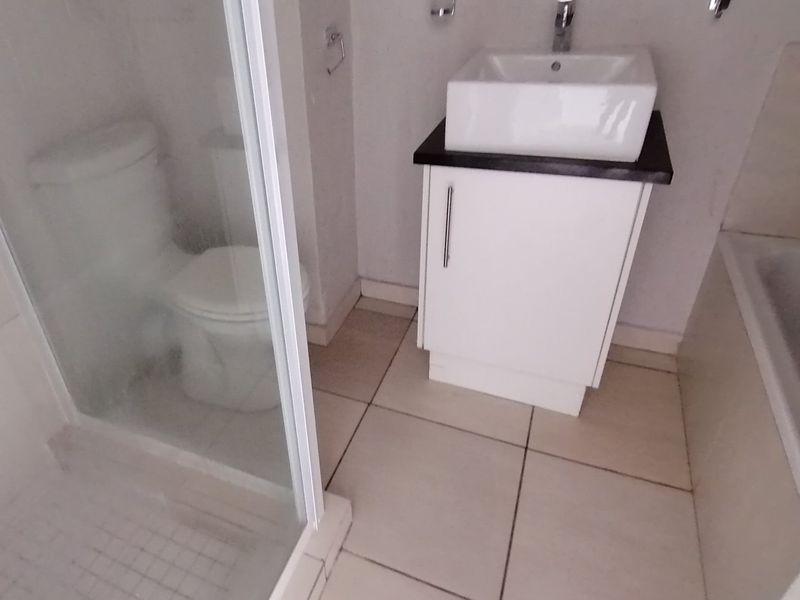 A functional bathroom featuring a vessel sink with vanity cabinet, a separate shower enclosure, and tiled flooring.