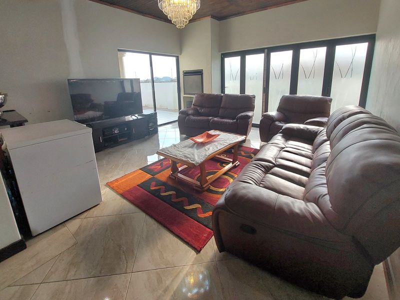 Spacious living room featuring tiled floors, a timber ceiling, a built-in fireplace, and large sliding glass doors providing access to the outdoor area.