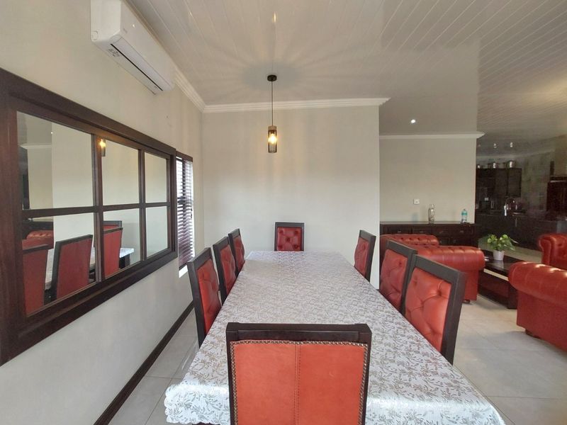 Open-plan dining and living area featuring tiled flooring, coved ceilings, and a wall-mounted air conditioning unit.