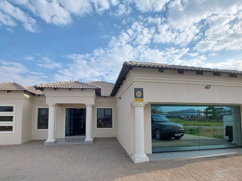 Front elevation of a modern house featuring a paved driveway, concrete columns, and a large glass-fronted garage.