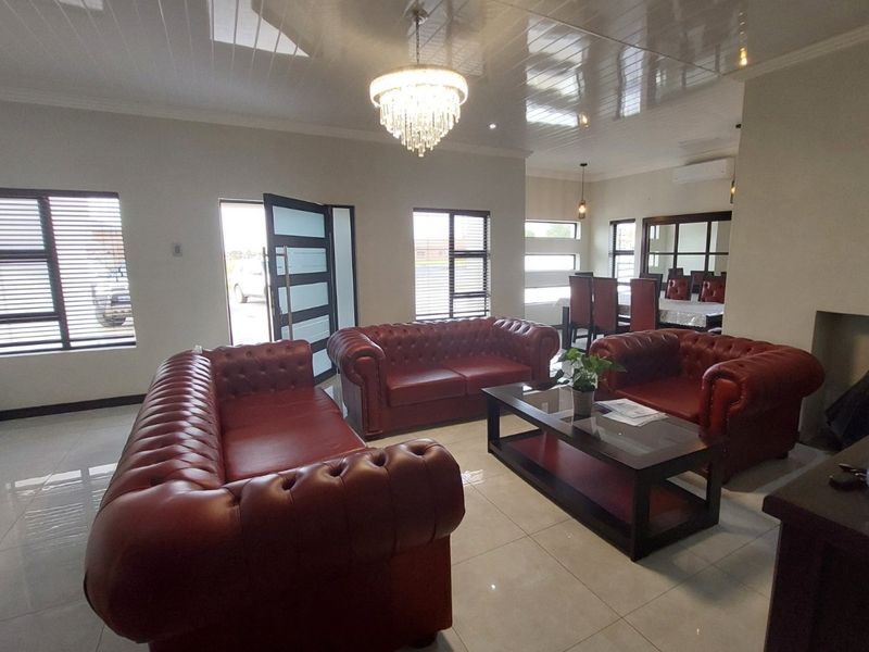 Spacious open-plan living and dining area featuring glossy ceiling panels, large windows, and polished tiled flooring, creating a bright and modern atmosphere.