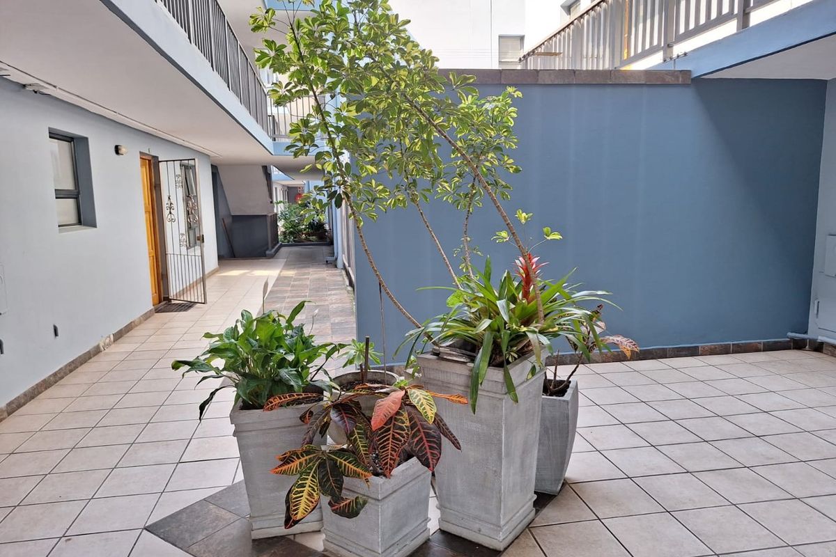 A paved outdoor courtyard area within an apartment complex, featuring tiled flooring, security gates, and access to surrounding residential units.