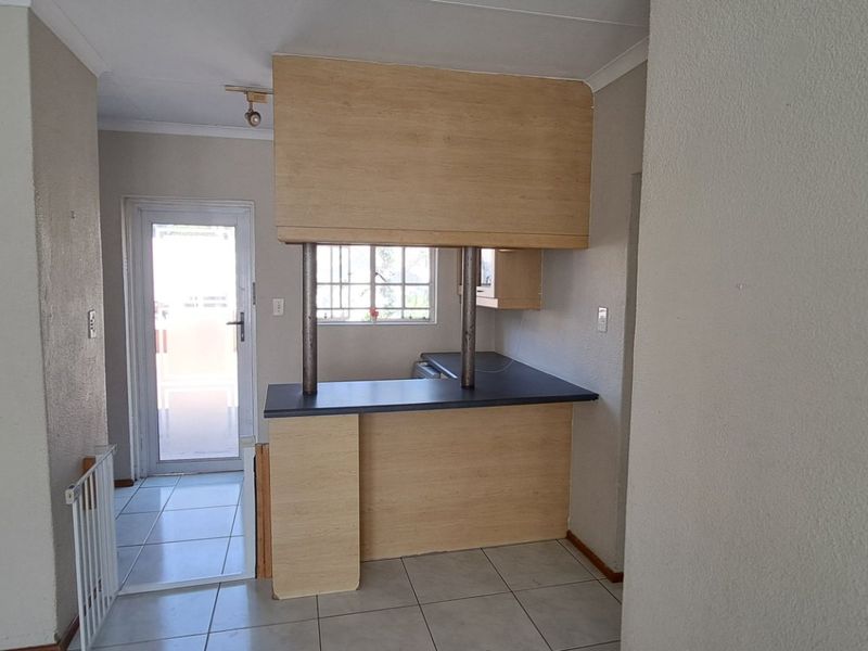 A functional kitchen area featuring a breakfast bar, laminate cabinetry, and tiled flooring, with direct access to an exterior door.