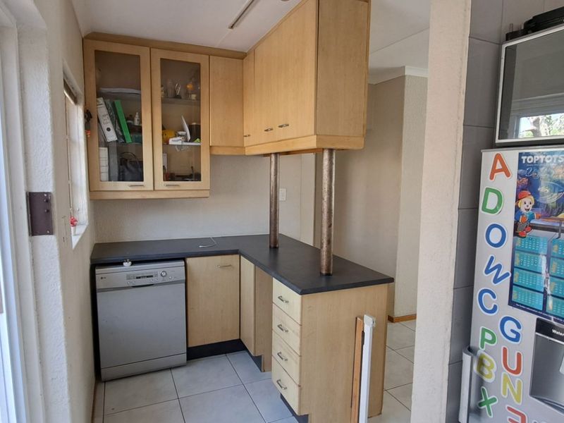 A functional scullery area featuring built-in wooden cabinetry, laminate countertops, and tiled flooring, providing additional storage and workspace adjacent to the main kitchen.