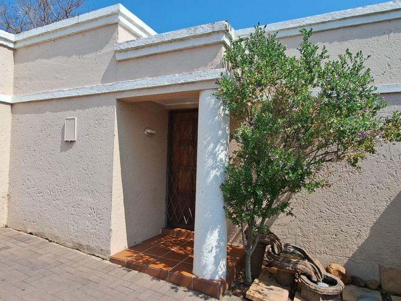 Front entrance of the apartment featuring a paved driveway, roller garage door, and a covered porch with a decorative column.