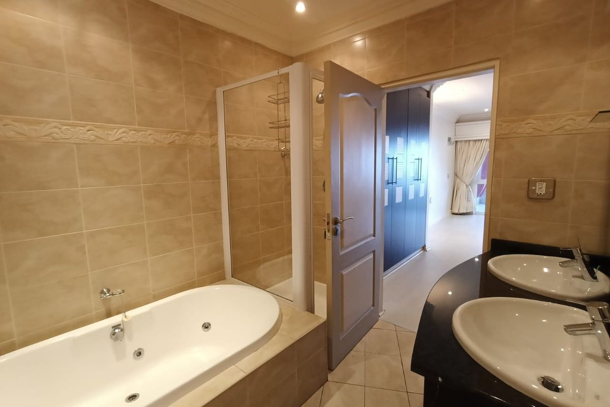 A well-appointed bathroom featuring a built-in jetted bathtub, a separate shower enclosure, and a double vanity with a dark countertop.