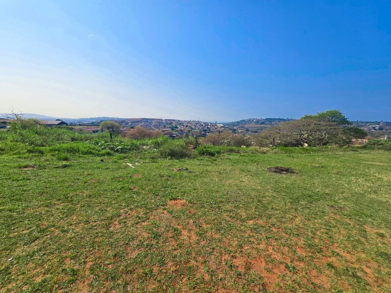 A wide-angle view of the vacant residential land, showcasing the natural landscape and surrounding neighborhood vistas.