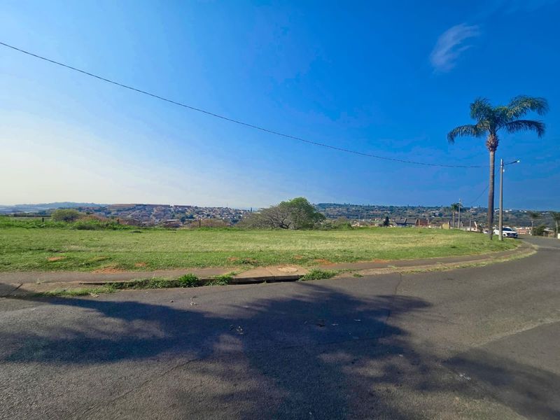 A vacant residential plot of land featuring a gentle slope, clear street access, and expansive views of the surrounding neighborhood.