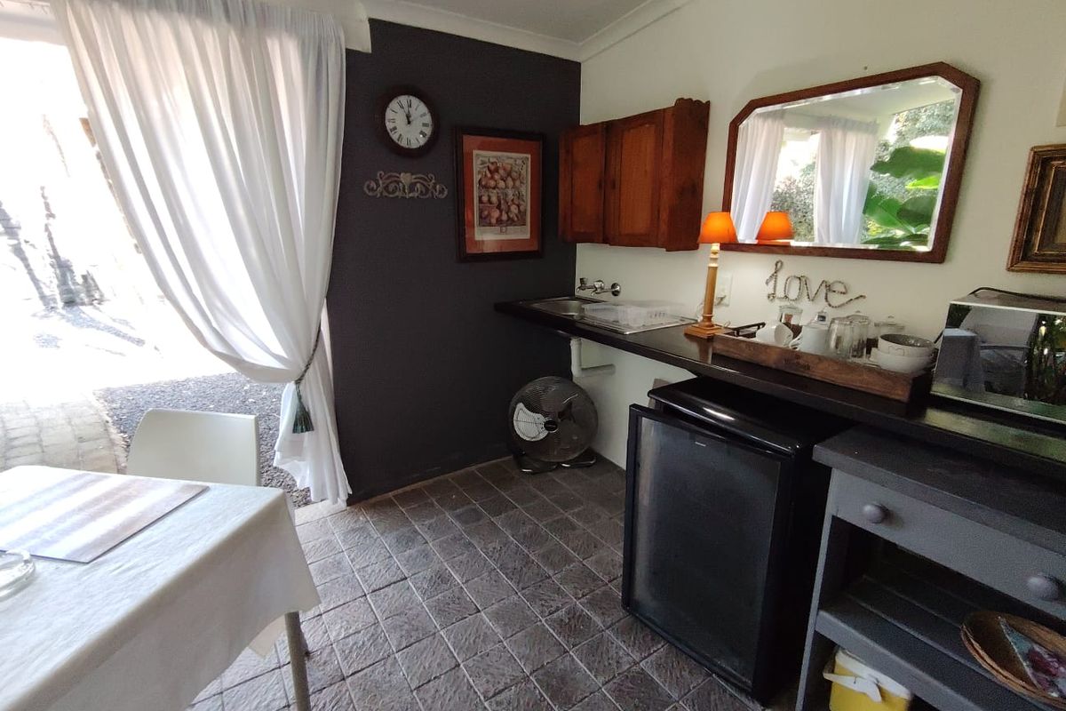 A compact kitchen area featuring tiled flooring, built-in cabinetry, and a sink, with direct access to an outdoor patio area.