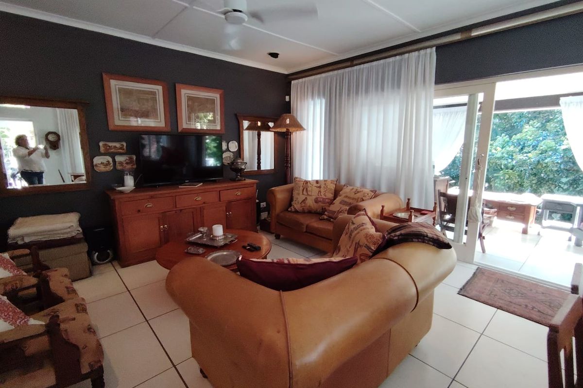 A comfortable living room featuring tiled flooring, a ceiling fan, and large sliding glass doors that provide direct access to the outdoor patio area.