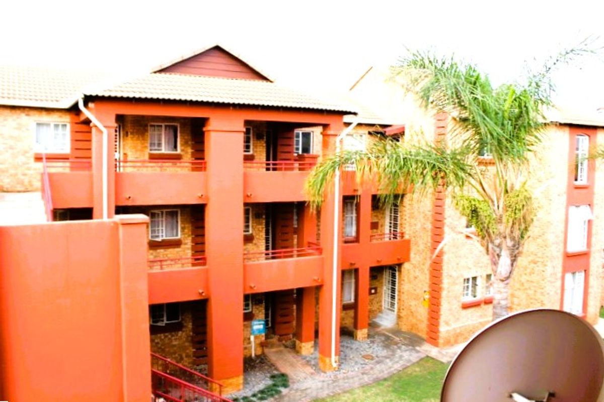 Exterior view of a multi-story apartment complex featuring brick facades, private balconies, and a paved ground-level courtyard area.