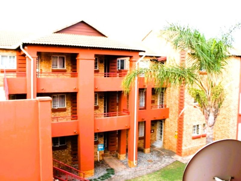 Exterior view of a multi-story apartment complex featuring brick facades, private balconies, and a paved ground-level courtyard area.