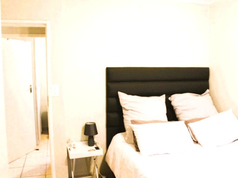 A bedroom featuring tiled flooring and a neutral interior, providing a functional space for rest.