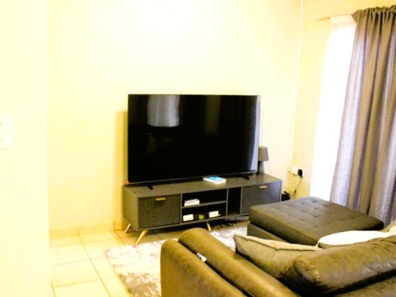 A living room area featuring tiled flooring and window treatments, providing a functional space for relaxation.